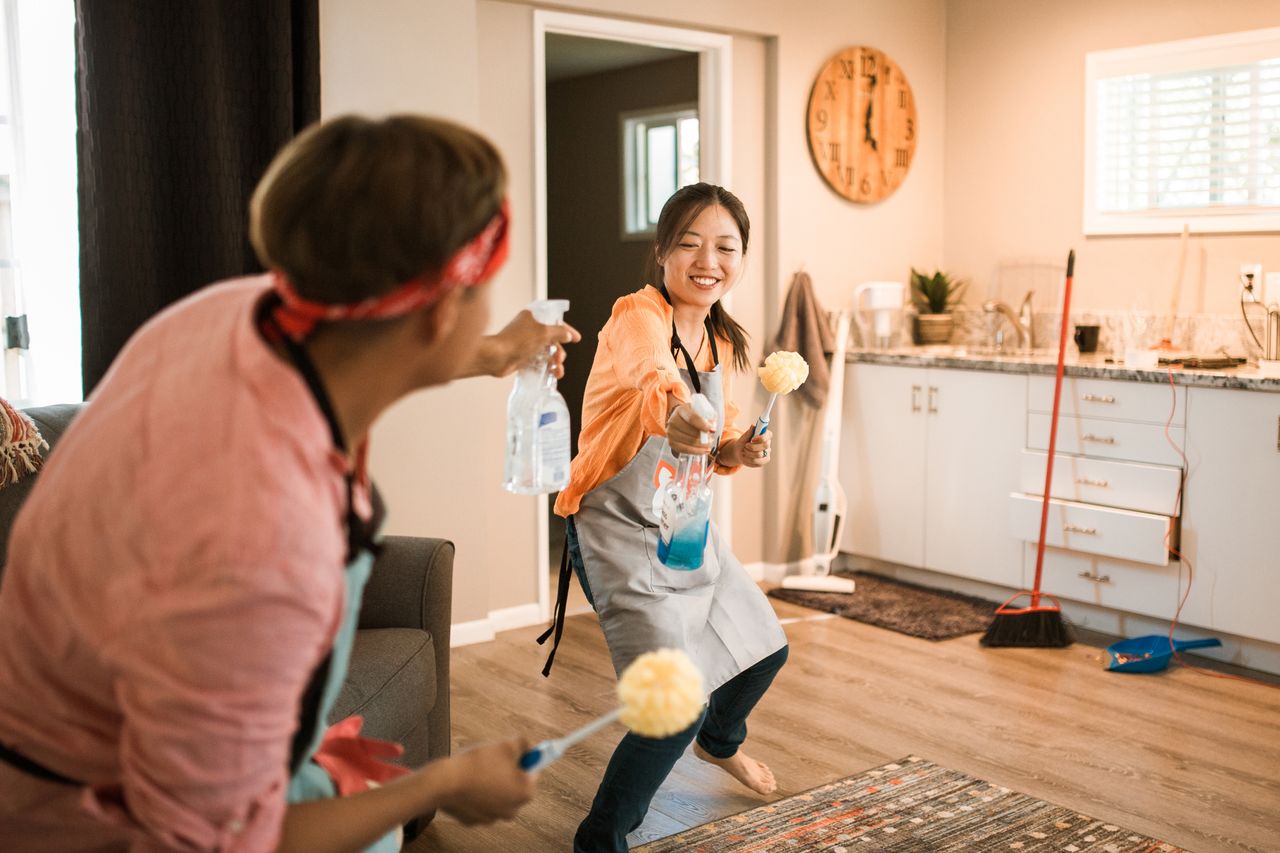 hero-img-01 Asian couple having fun while cleaning their home, enhancing a cheerful atmosphere.